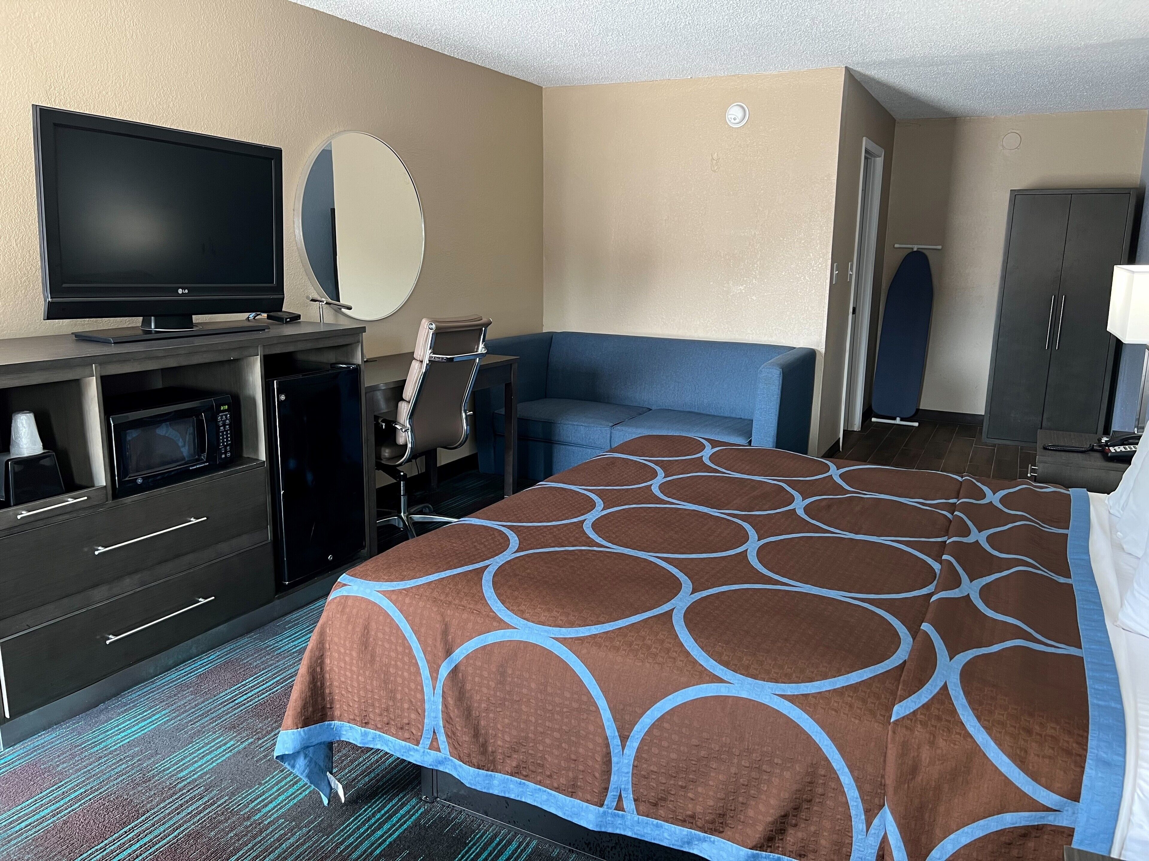 Une chambre d’hôtel équipée d’un lit, d’une télévision, d’un four à micro-ondes, d’une chaise, d’un bureau et d’une armoire.