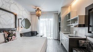 A modern hotel room with a large bed, a sitting area, a kitchenette, and a bathroom. - Hotel Bella Grace (Charleston)