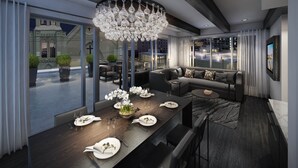 A modern dining area with a long table set for a meal, a chandelier, and a view of the cityscape through large windows. - Hotel Bella Grace (Charleston)