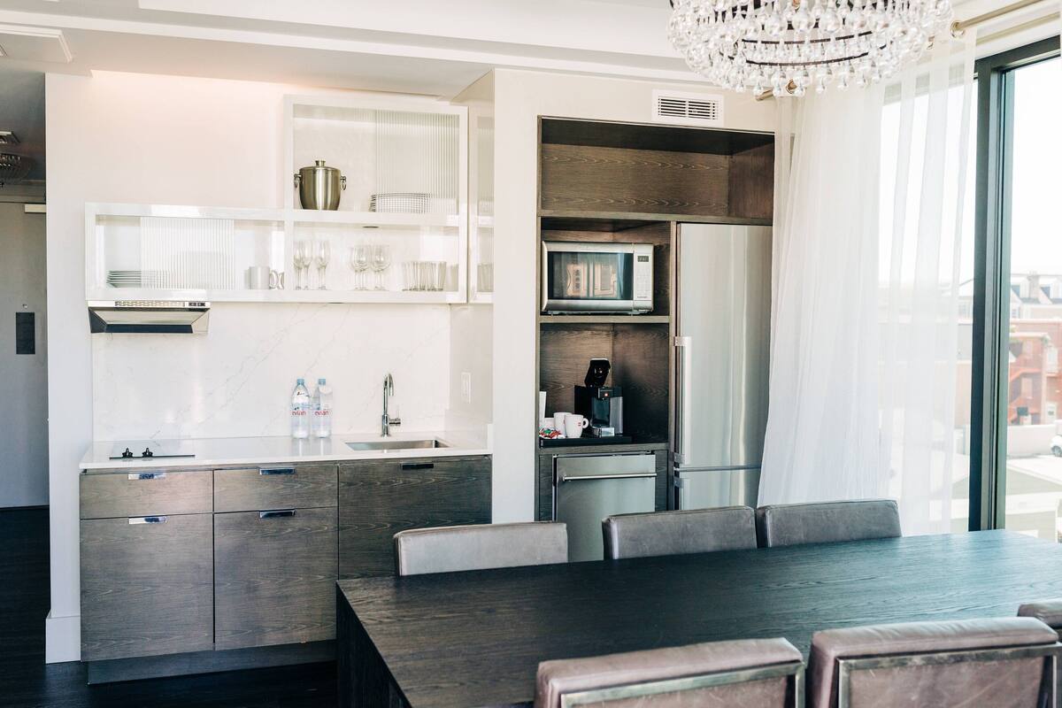 A modern kitchen with a dining area, built-in appliances, and a large window.