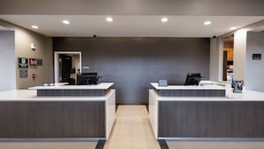 A reception area with two reception desks, a patterned wall, and a tiled floor. - Residence Inn by Marriott Oklahoma City Airport (Oklahoma City)