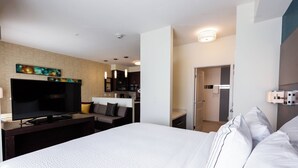 A hotel room with a large bed, a flat-screen TV, a sofa, and a kitchen area in the background. - Residence Inn by Marriott Oklahoma City Airport (Oklahoma City)