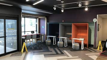 Un espacio de oficina moderno con un ventanal grande, un escritorio con computadora y varias zonas de estar.