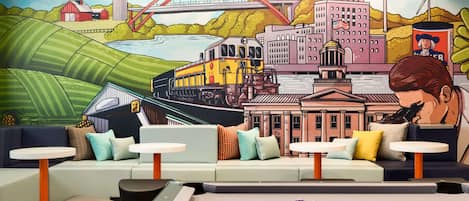 A billiards table with colorful balls, a mural of a cityscape, and a seating area with sofas and tables.