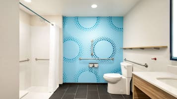 Ein modernes Badezimmer mit Dusche, Toilette und Waschbecken, mit blauer Wandverkleidung und dunklen Fliesen.