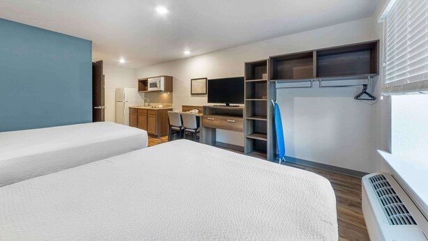 Een hotelkamer met een bed, een bureau met stoel, een televisie, een magnetron en een kledingkast.