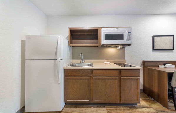 A compact kitchen with a refrigerator, microwave, sink, and wooden cabinets. - Extended Stay America Select Suites Deerfield Beach (Deerfield Beach)