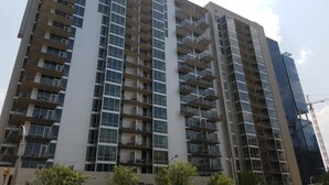 Un edificio residencial de gran altura con múltiples balcones, ventanas amplias y un diseño arquitectónico moderno.