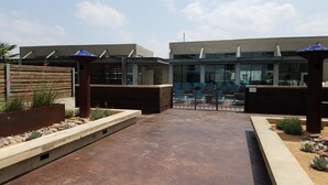 Un edificio moderno con fachada de vidrio, un patio de concreto y una valla de madera.