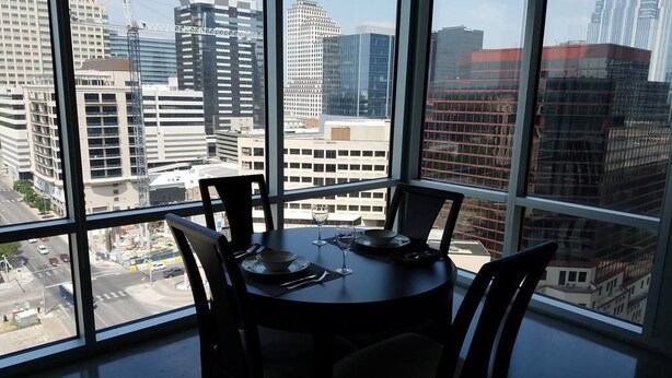 Un comedor con una mesa redonda y sillas, amplias ventanas con vistas a la ciudad.