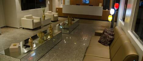 A hotel lobby with a reception desk, seating area, and a large window.