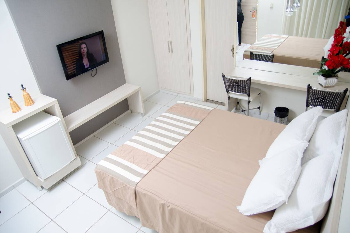 A bedroom with a bed, a TV, a desk, and a chair.