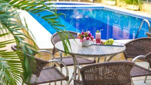 A poolside area with a round table, wicker chairs, and a potted plant. - Vitoria Palace Hotel (Mossoro)