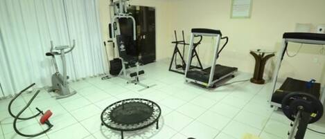A gym with various exercise equipment including a treadmill, elliptical, and weight machines.