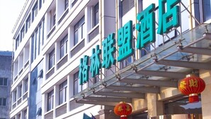 Ein Hotel mit moderner Fassade, mehreren Etagen und einer auffälligen Schilderung mit chinesischen Schriftzeichen.