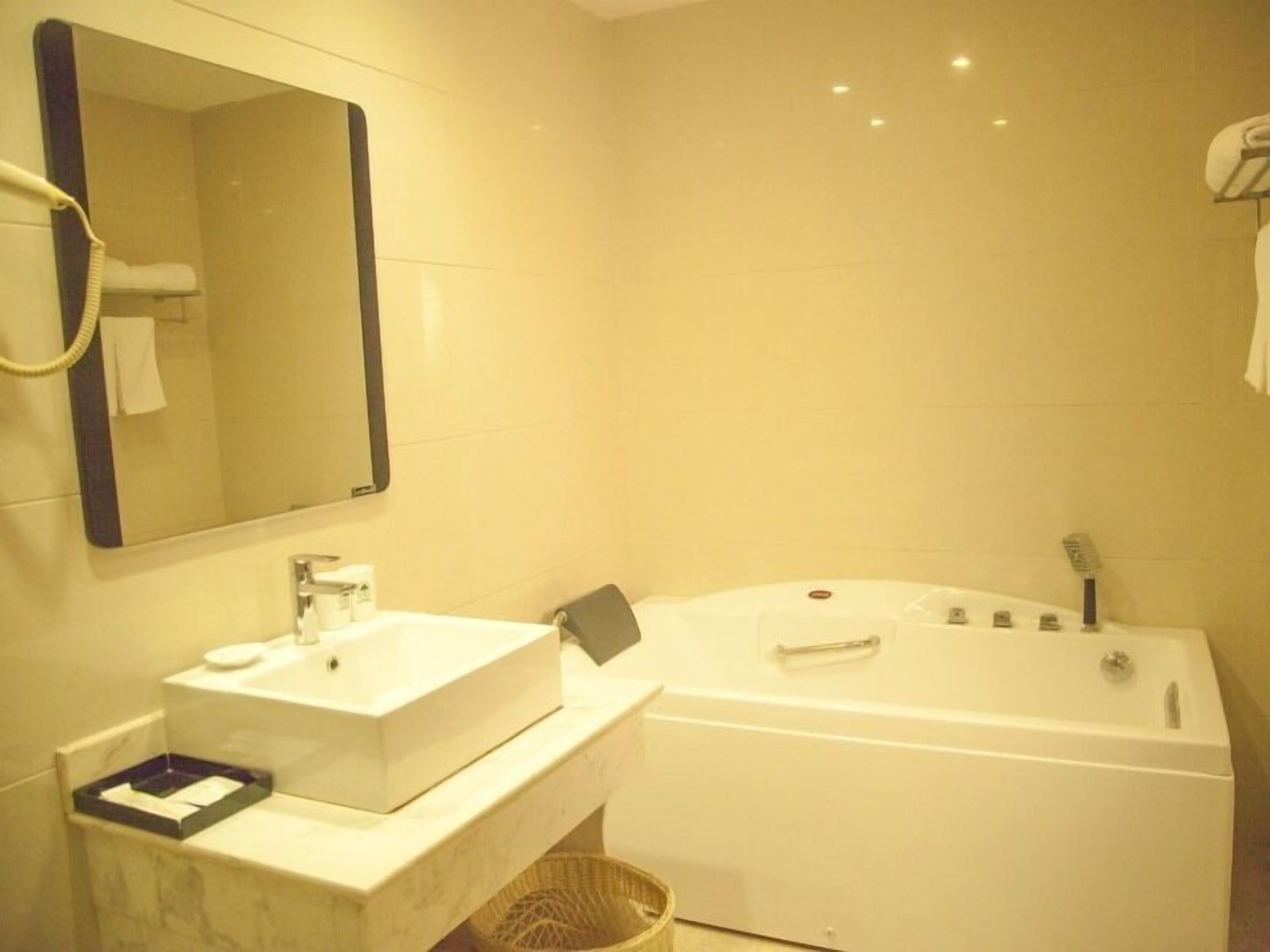 A bathroom with a white sink, mirror, and bathtub.