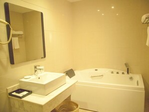 A bathroom with a white sink, mirror, and bathtub. - GreenTree Alliance Nantong Rugao Jiuhua Town Government Hotel (Nantong)