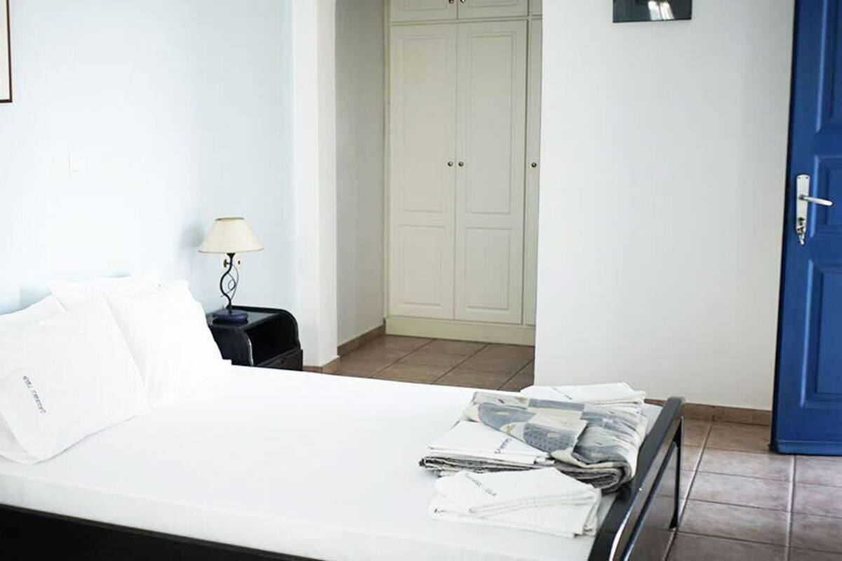Un dormitorio con cama, mesita de noche, lámpara, armario y una puerta azul.
