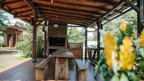 An outdoor patio with a stone fireplace, wooden benches, and a grill area. - Estrella del Monte (Puerto Iguazú)