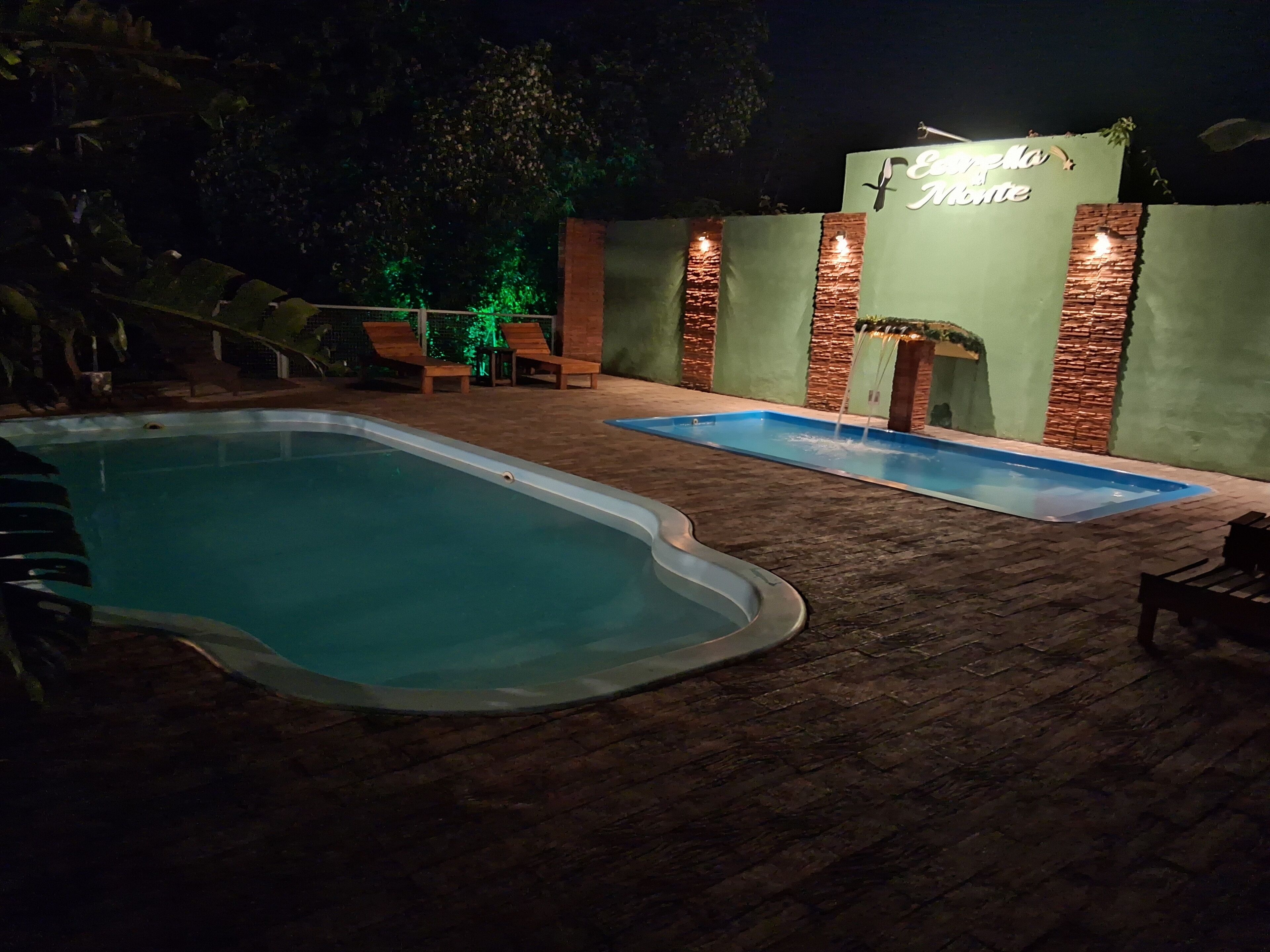 Un espace piscine nocturne comprenant deux piscines, une terrasse en briques et un panneau indiquant « Casa da Moita ».