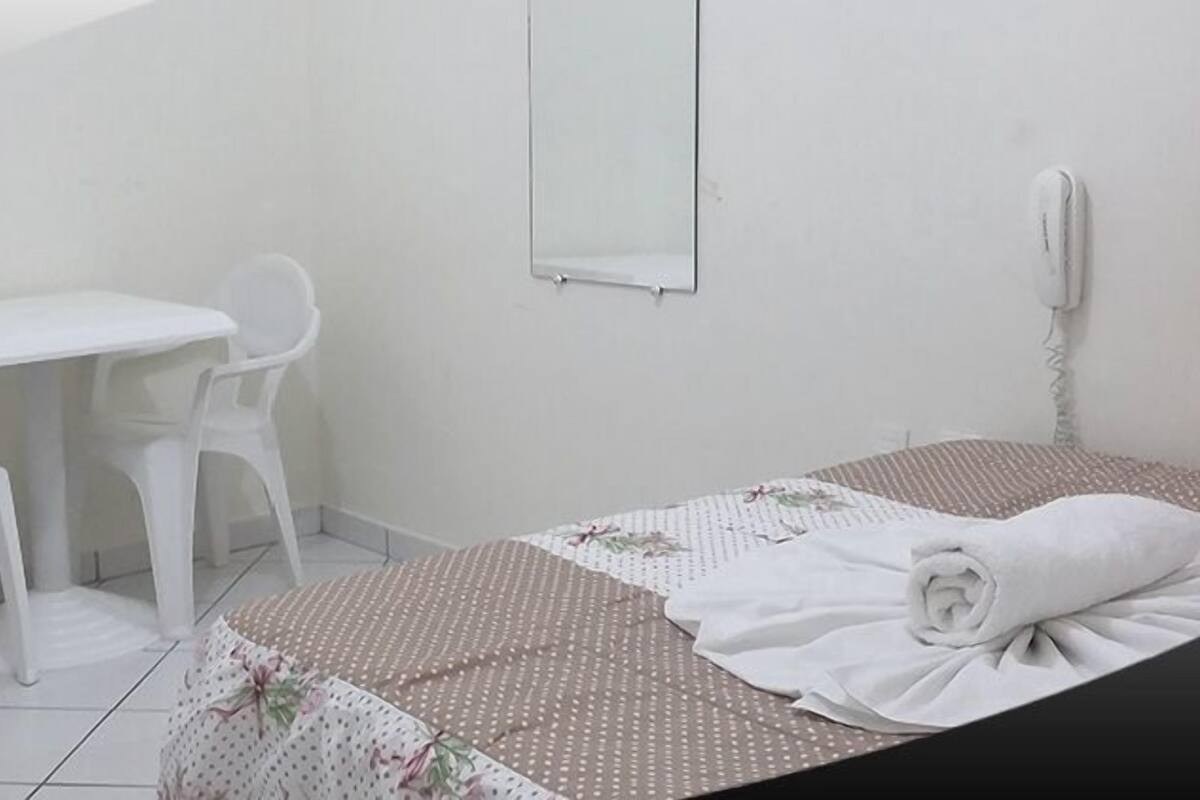 A small, clean room with a bed, a desk, and a chair.
