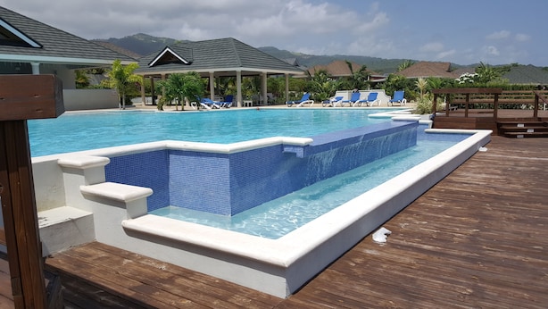 A swimming pool with a wooden deck, lounge chairs, and a view of mountains. - Ocho Rios Villa at Coolshade IX (St. Ann's Bay)