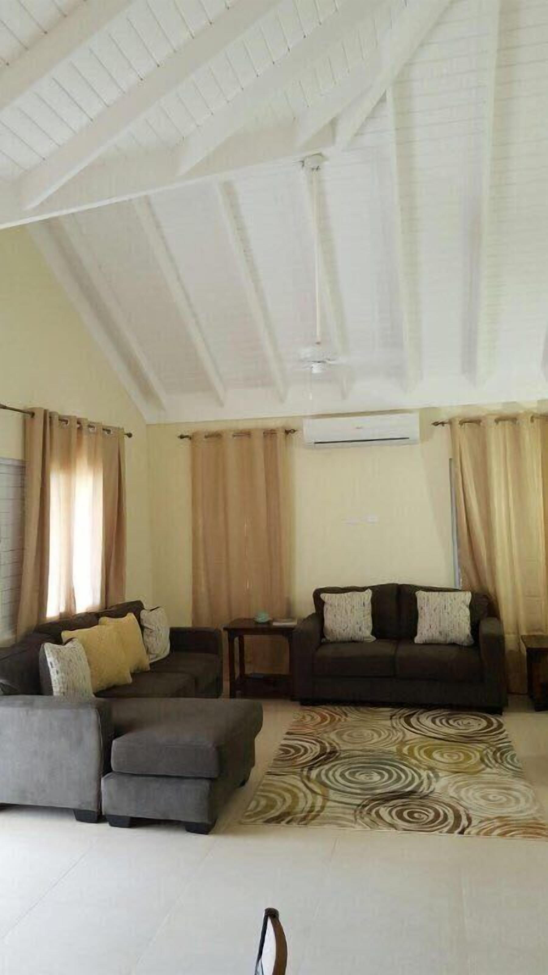 A spacious living room with a high ceiling, two sofas, a coffee table, and a patterned rug.