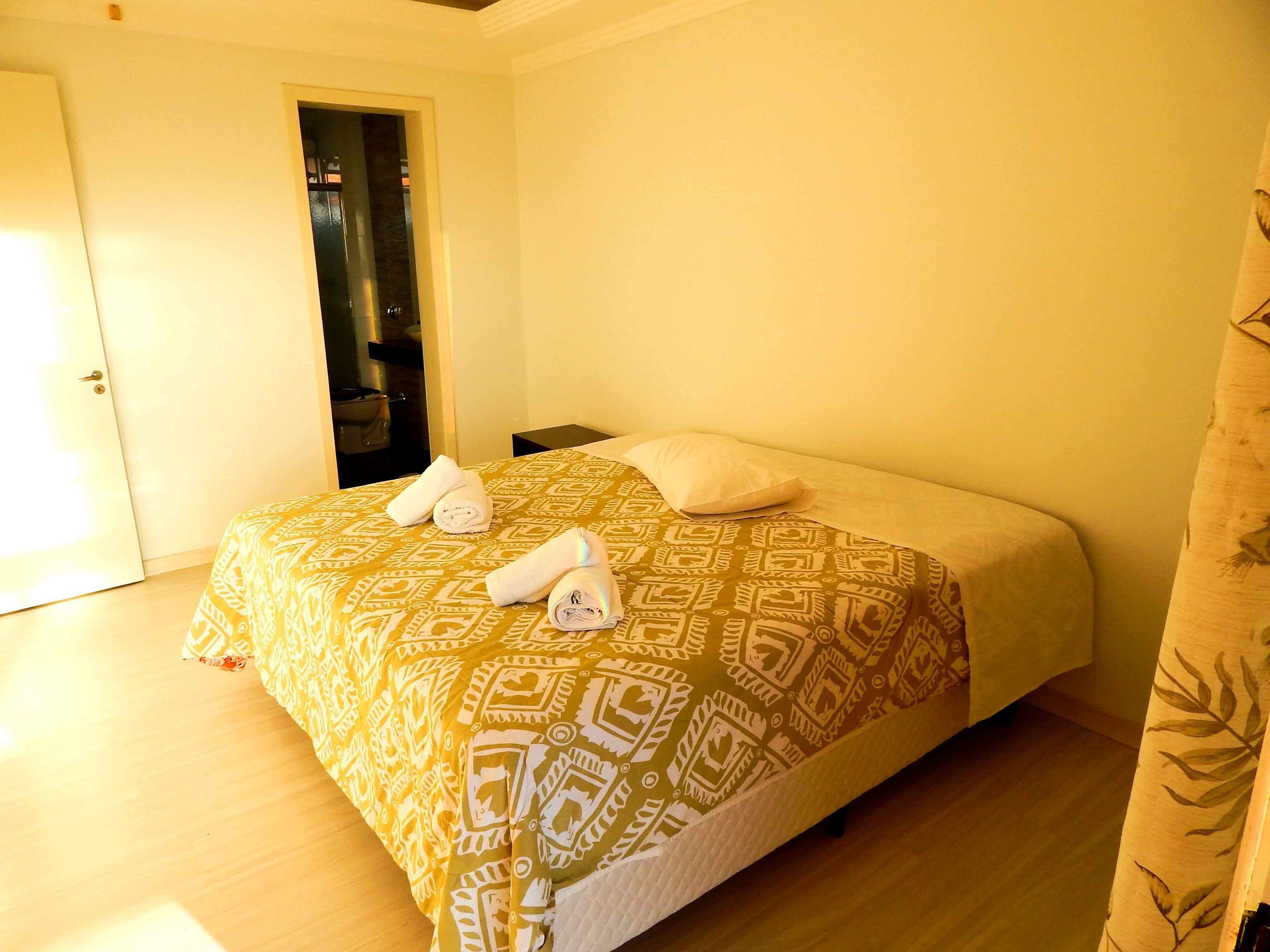 A hotel room with a bed, a door, and a bathroom visible through an open door.