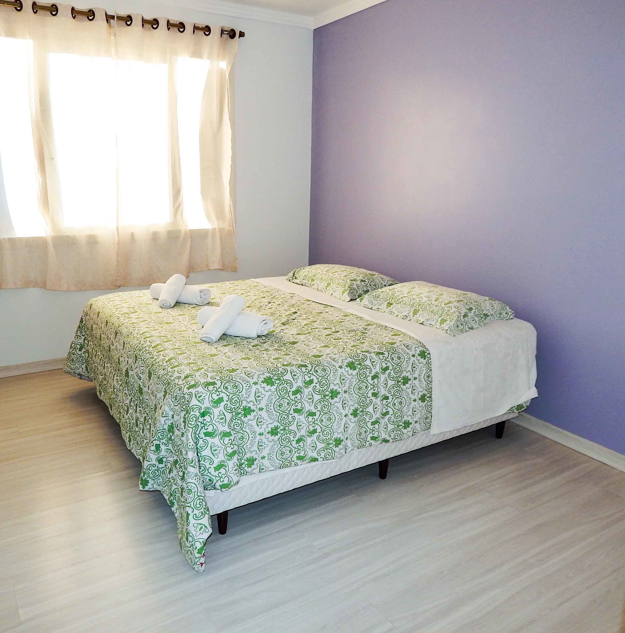 A bedroom with a bed, two pillows, and a window with curtains.