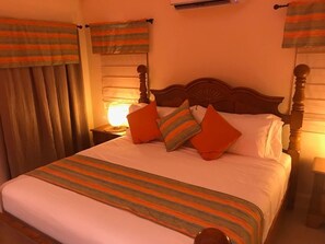 A neatly made bed with a striped bedspread, two pillows, and a wooden headboard. - Ocho Rios Villa at Coolshade X (St. Ann's Bay)