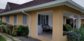 A house with a covered porch, a chair, and a window. - Ocho Rios Villa at Coolshade X (St. Ann's Bay)