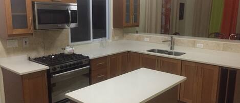 A kitchen with wooden cabinets, a microwave, a stove, and a sink.