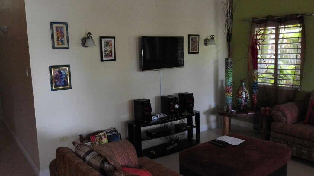 Un soggiorno con televisione, casse acustiche e quadri appesi al muro.