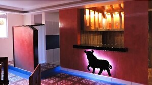 A hotel lobby with a red wall, a black silhouette of a sheep, and a blue carpet.