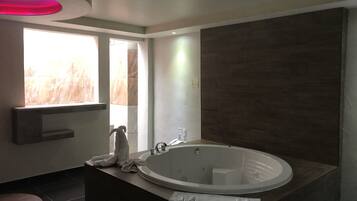 A modern bathroom with a freestanding bathtub, a vanity with a mirror, and a window providing natural light.