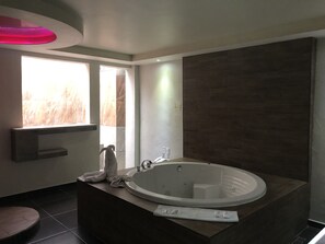 Un baño moderno con una bañera independiente, un tocador con espejo y un ventanal que proporciona luz natural.