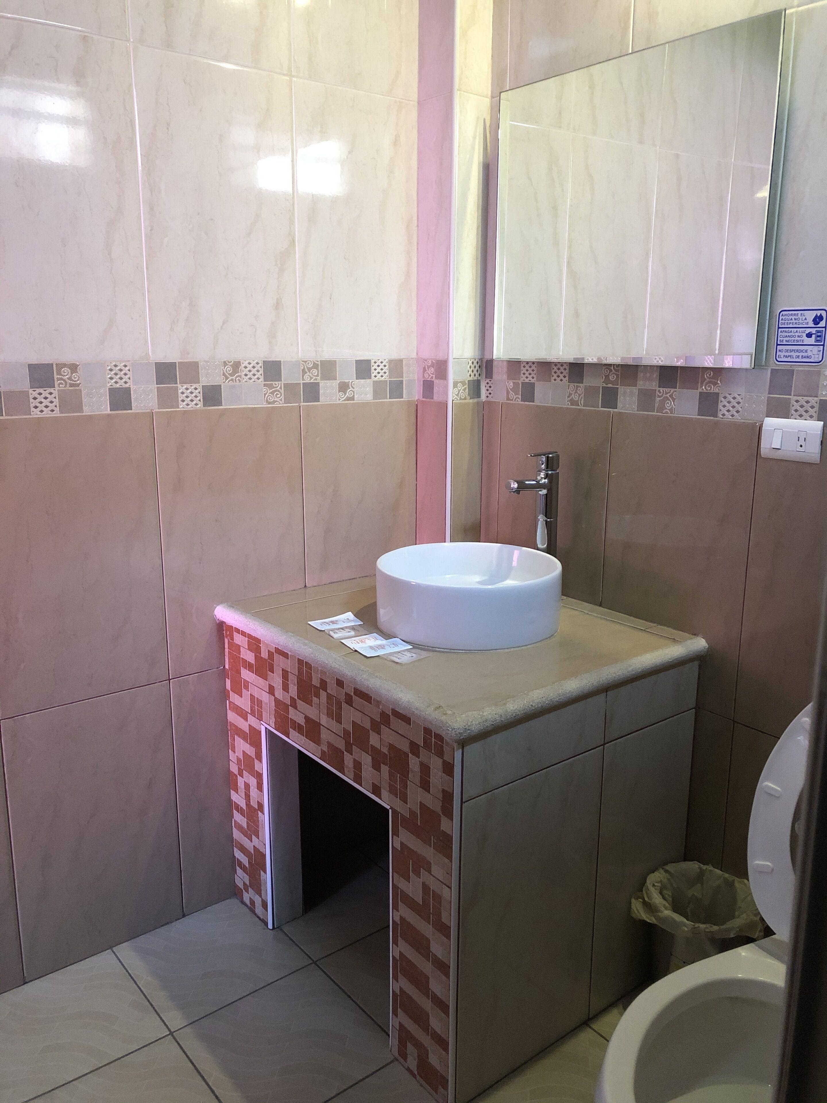 Une salle de bain avec un lavabo blanc, un miroir et des toilettes.