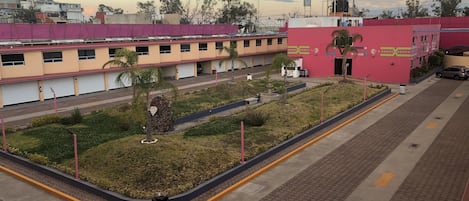 A hotel with a parking area, a landscaped garden, and a building with a pink facade.