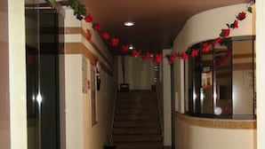 A hallway with a staircase leading to an upper floor, decorated with red flowers.