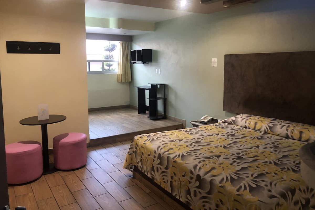 Un dormitorio con cama, escritorio, silla y una pequeña mesa con otra silla.