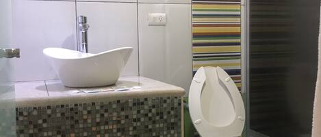 Un baño con un lavamanos blanco, un inodoro y una zona de ducha.