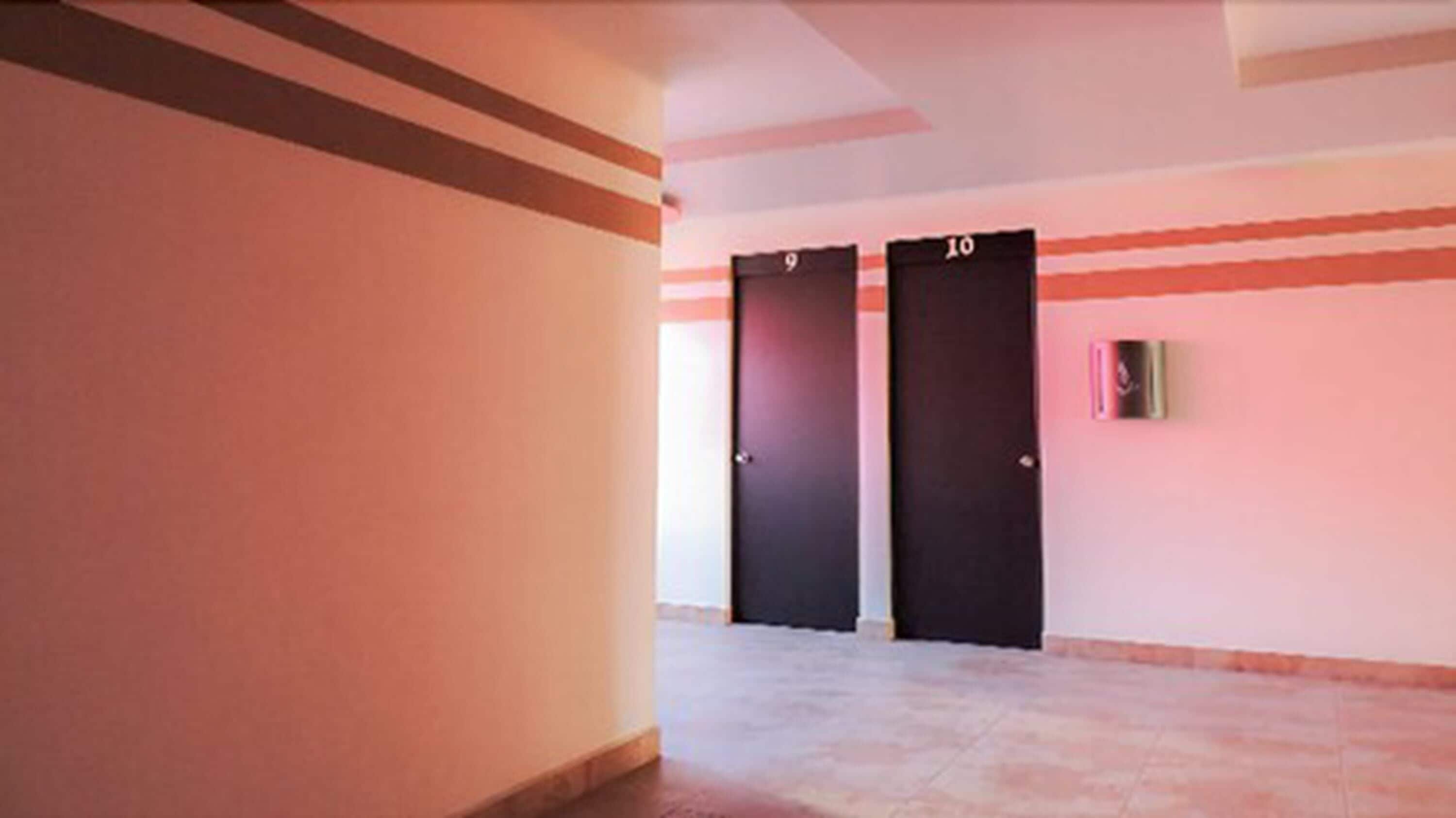 A hallway with two doors labeled 9 and 10, a light switch, and a tiled floor.
