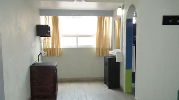 A bedroom with a bed, a dresser, a mirror, and a window with curtains.