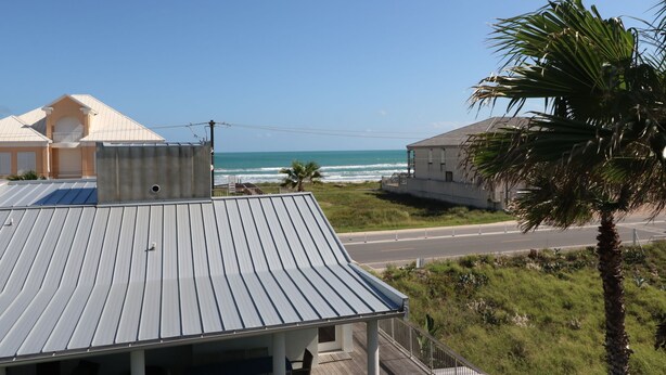 A coastal building with a metal roof, a balcony, and a view of the ocean.