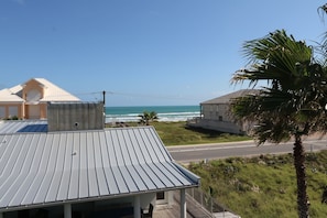 Un bâtiment situé sur la côte, doté d’un toit en métal, d’un balcon et offrant une vue sur l’océan.