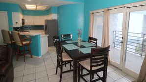 A kitchen with white cabinets, a refrigerator, and a dining area with a table and chairs.