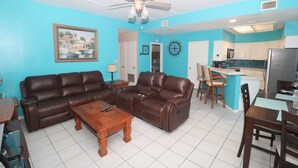 A living room with a brown leather sofa, wooden coffee table, and a ceiling fan.