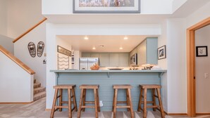 Una cocina moderna con una isla central, taburetes de madera y una escalera.