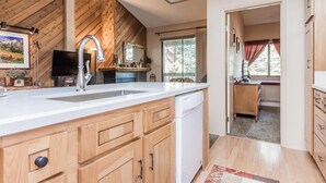 A kitchen with wooden cabinets, a white countertop, a built-in dishwasher, and a ceiling fan. - Crestview B46 (Mammoth Lakes)