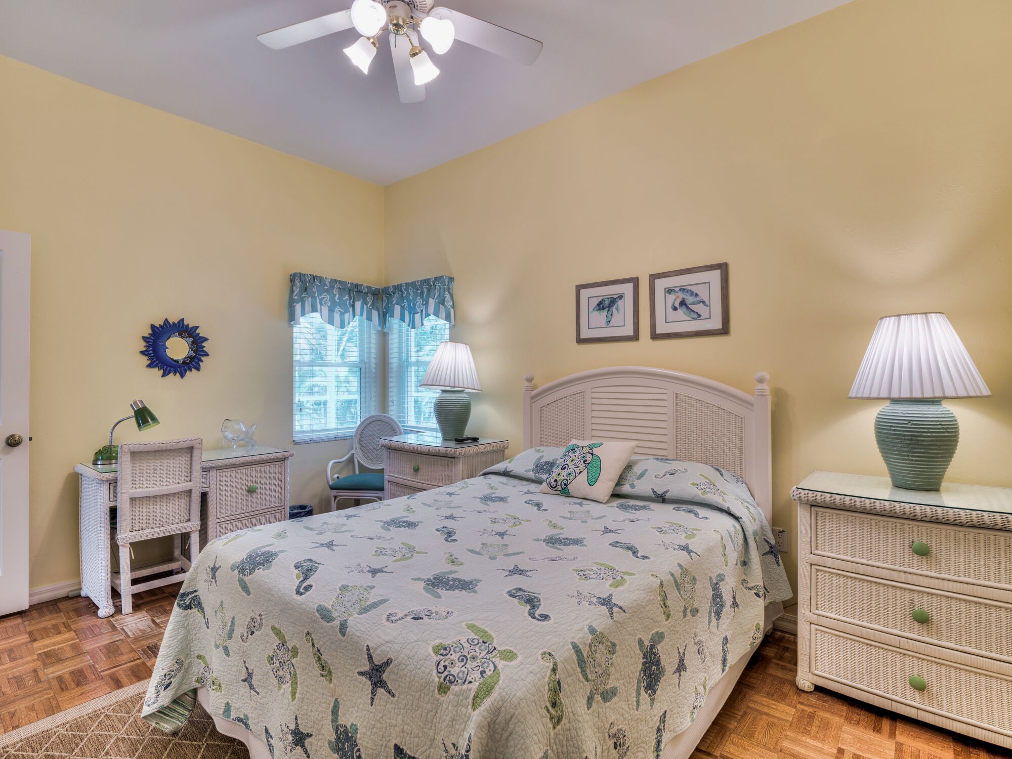 A bedroom with a bed, two nightstands, a chair, a desk, and a window with curtains.